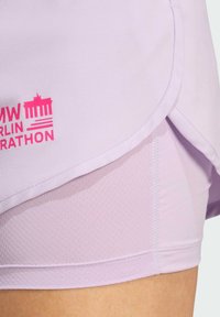 Lichtpaarse hardloopshorts van ademend materiaal, met een gebogen zoom en een opvallend roze "BMW Berlin Marathon" logo.