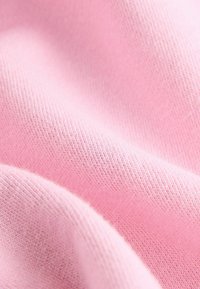 Tessuto rosa chiaro con una texture morbida, caratterizzato da un fine motivo a maglia e da una superficie liscia, che esalta subtilmente il suo aspetto leggero e arioso.
