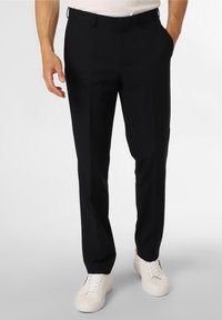 Pantalones negros ajustados de tela texturada con un corte slim, con frente plano y dos bolsillos laterales, combinados con zapatillas blancas.