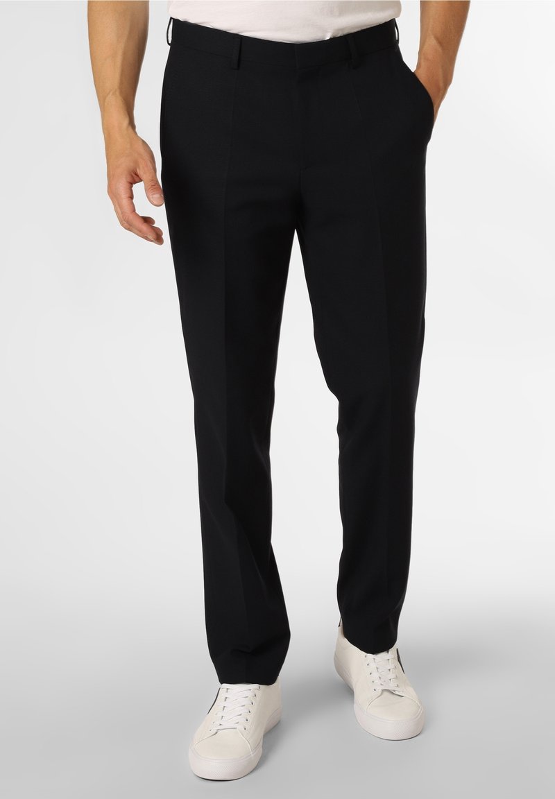 Pantalones negros ajustados de tela texturada con un corte slim, con frente plano y dos bolsillos laterales, combinados con zapatillas blancas.