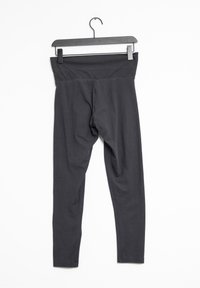 Zwarte, rekbare leggings met een brede tailleband en een gladde textuur, hangend aan een zwarte plastic hanger tegen een witte achtergrond.