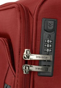 Roter, strukturierten Koffer mit zwei silbernen Reißverschlüssen, einem Zahlenschloss und einem Griff an der Seite für einfachen Transport.