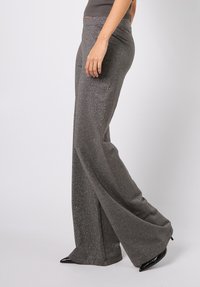 Grå vide bukser laget av et glitrende stoff, med høy midje og glatt tekstur, med en svak utvidelse nederst.