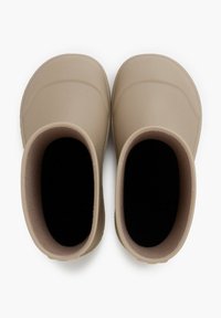 Bottes en caoutchouc beiges avec un design à bout arrondi, intérieur texturé et doublure noir contrastante. Construction légère et imperméable.