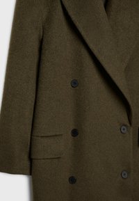 Dubbelzijdige olijfgroene jas van getextureerde wol, met zwarte knopen en een brede kraag, voorzien van een zijzakdetail.