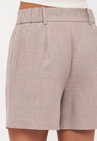Shorts galbeni deschis, texturat, cu un tiv strâns, având pliseuri pentru formă și un tiv bine definit. Potrivite pentru purtarea casual.