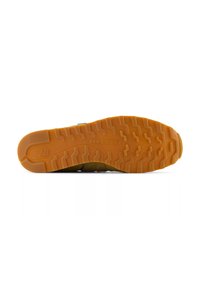 Gelbe und braune Sneaker-Sohle mit einer strukturierten Gummi-Oberfläche, die ein Zickzack-Muster aufweist und das eingeprägte "New Balance"-Logo zeigt.