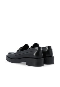 Mocassins en cuir noir avec une finition brillante, arborant un design à bout arrondi et de petits talons carrés, présentant des accents de couture détaillés.