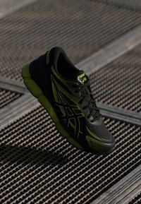 Sapatilha atlética preta e verde neon com um upper texturizado, padrão lateral ousado, sola acolchoada e design com atacadores.