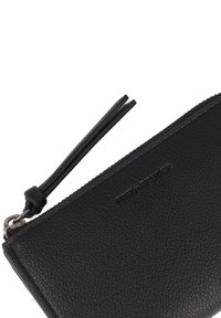Clutch de cuero negro con un acabado texturizado, que cuenta con un cierre de cremallera y una correa para la muñeca. Tiene un logotipo en relieve en la superficie.