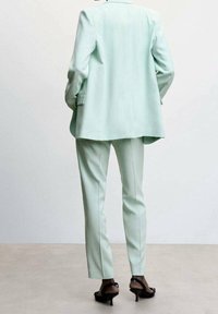Mintgrøn skræddersyet jakkesæt med en lang blazer og slim-fit bukser, lavet af glat stof med rene linjer og subtile syninger.