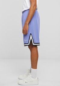 Lilla sportskort med sort og hvid kant, med et broderet logo. Lavet af letvægtsstof; elastisk talje for komfort.
