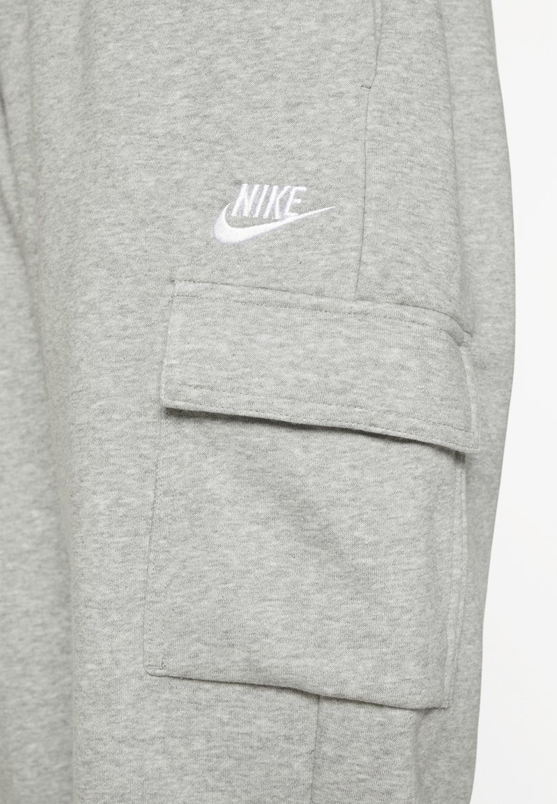 Pantaloni sportivi grigi in tessuto liscio, dotati di una tasca laterale con pattina e di un logo Nike ricamato bianco sul davanti.