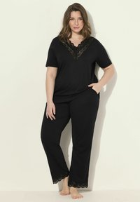 Set di abbigliamento da casa nero, composto da una maglietta a maniche corte con scollatura in pizzo e pantaloni abbinati con rifiniture in pizzo all'orlo. Tessuto morbido e elasticizzato.