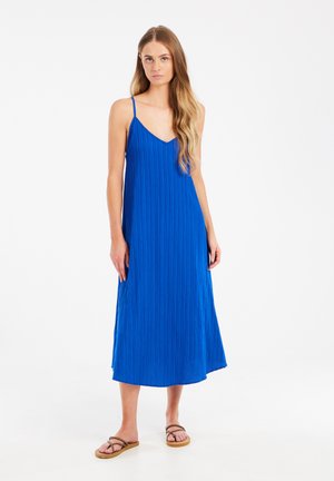 Sleevless, midi-length dress in vibrant blue, featuring a textured design and V-neckline, paired with flat sandals.