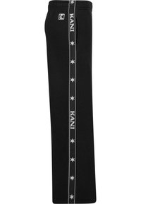 Črne trenirke imajo stransko črto z belimi zvezdami in besedilom "KANI", so narejene iz mehkega blaga, z elastičnim pasom in žepi.