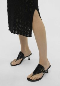 Černé sandály na podpatku s v-čkovým páskem, vyrobené z hladké kůže, s malou zlatou přezkou a otevřenou špičkou.