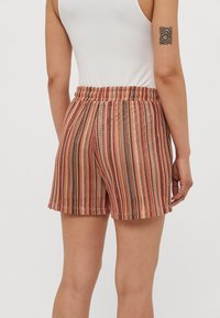 Pantaloni corti a righe nei toni di rosa, marrone e crema, con vita elastica e una vestibilità rilassata realizzati in un tessuto testurizzato.