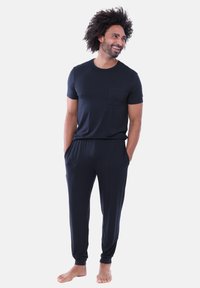 Mörkblå mjukisset med kortärmad skjorta med bröstficka och byxor med dragsko. Tyget verkar mjukt och har en avslappnad passform.