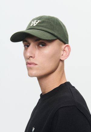 Olive green baseball cap with a curved brim and embroidered white logo on the front. Worn with a black crewneck sweatshirt.