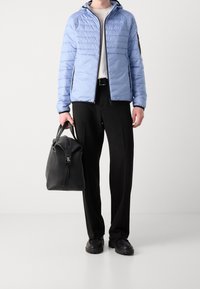 Ljusblå pufferjacka med horisontell söm, svart dragkedja, vit t-shirt, svarta byxor och svart strukturerad läderväska. Svarta skor.