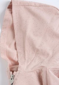 Haut à capuche rose avec une texture douce, ornée de paillettes argentées et d'un tirette en forme de cœur. Le matériau semble confortable et décontracté.