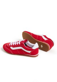 Sneakers in suede rosso con accenti bianchi, caratterizzati da un design classico, lati perforati e una suola in gomma testurizzata color gomma.