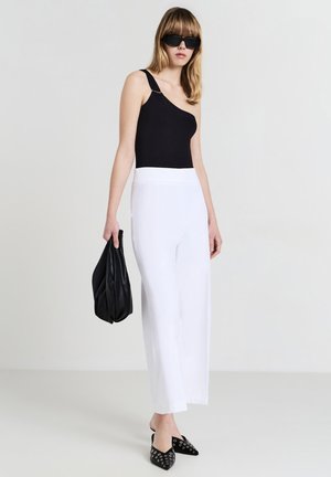 Black one-shoulder bodysuit, white wide-leg pants, black bag, and black pointy flats with metal accents. Smooth, solid colors with minimal design.
