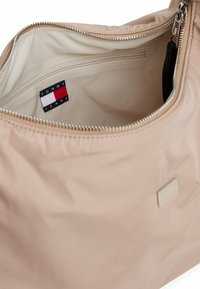 Interno di una borsa a spalla in nylon rosa, con una tasca con zip e un'etichetta di marca. Tessuto liscio e hardware con zip argentata.