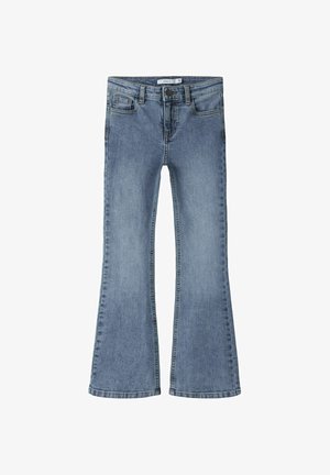 Jasnoniebieskie jeansy z denimu z rozszerzanymi nogawkami, z przodem na guziki i zamek oraz z pięcioma kieszeniami, pokazane ułożone na płasko na białym tle.