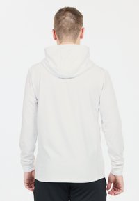 Hvid langærmet hoodie med fleece-tekstur, en stor hætte og tætsiddende manchetter. Bagsiden er ensfarvet uden synlige logoer eller mønstre.