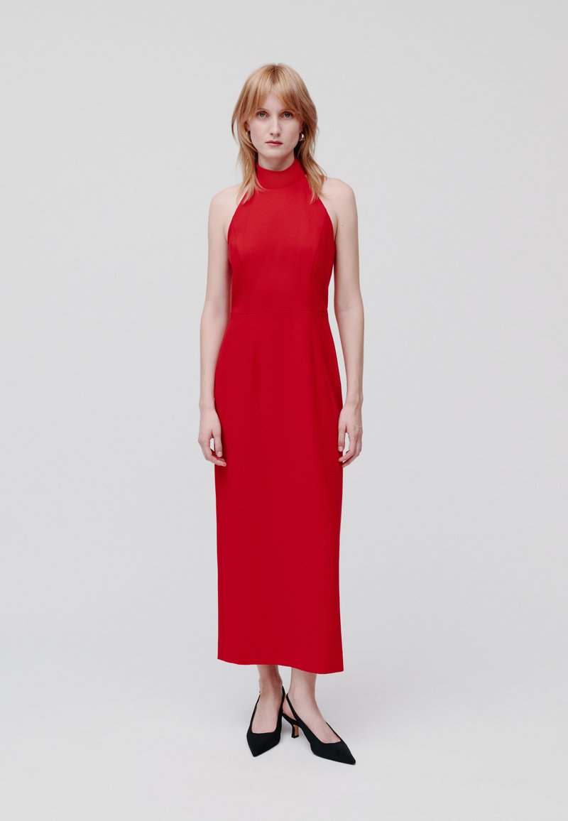 Rode halterneck midi-jurk met een aansluitende lijfje en een rechte silhouet, met een gladde textuur en minimale accessoires. Zwarte puntige hakken.