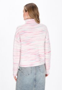 Maglione lavorato a maglia con colletto alto, caratterizzato da un motivo a righe rosa e bianche. Indossato con una gonna di jeans a vita alta, che mostra un fit rilassato.