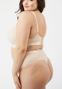 Beige lingerieset met een naadloze beha met verstelbare bandjes en bijpassende hipsteronderbroek, beide gemaakt van een soepele, rekbare stof.