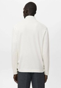 Langärmliges Hemd in Cremefarbe mit lockerem Schnitt und geripptem Kragen, ausgestattet mit glatter Textur und Seitenschlitzen am Saum.