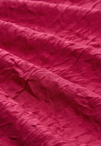 Tissu froissé en magenta profond, présentant une surface texturée avec des plis et des motifs irréguliers, mettant en valeur son apparence douce et tissée.