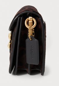 Leopard print handbag with black leather accents, gold hardware, zip closure, and a detachable tag. Textured surface for added detail.
