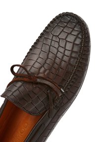 Braune Lederloafers mit einem geprägten Krokodilmuster, ausgestattet mit einem dünnen, dunkelbraunen Schnürdetail und einem glatten, kontrastierenden Innenfutter.