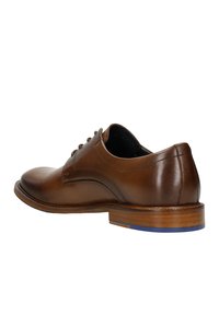 Scarpa in pelle marrone con punta arrotondata, texture liscia e cuciture decorative, con un accento blu sulla suola. Design con lacci.