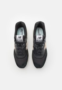 Chaussures de sport noires et grises en mesh et daim, avec des lacets, une semelle coussinée et un logo sur le côté.