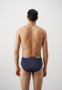 Temno modri kopalni boksarji iz mehkega blaga, z širokim elastičnim pasom, označenim z "PUMA" v beli barvi, ter s sleek, prilegajočim se dizajnom.