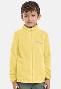 Gelbe Fleecejacke mit hohem Kragen, durchgehendem Reißverschluss und Logodetail auf der linken Brust. Weiche Textur und eng anliegende Passform für Wärme.