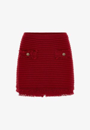 Red ribbed mini skirt with frayed hem, featuring two patch pockets with circular gold-tone buttons on the front.