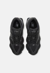 Black athletic shoes with mesh and suede materials, featuring a textured sole, laces, and a branded logo on the tongue.