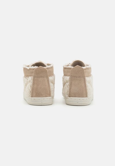 Stivali ankle in suede beige con pelliccia sintetica cream testurizzata, colletto imbottito e suola in gomma bianca. I dettagli cuciti sul tallone si estendono verso l'alto.