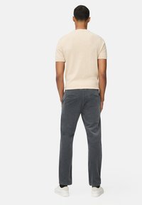 Beige, korte mouwen sweater met een slim-fit ontwerp, gecombineerd met grijze corduroy broek. De broek heeft een textuur en twee achterzakken.