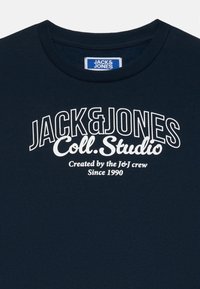 Marineblaues Sweatshirt mit rundem Halsausschnitt, mit weißem Text: "JACK&JONES Coll.Studio" und "Created by the J&J crew Since 1990."