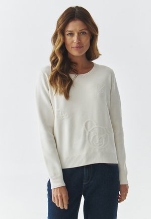 Maglione color crema in morbido knit con polsini e orlo a coste. Presenta design ricamati testurizzati, tra cui un orso e delle lettere.
