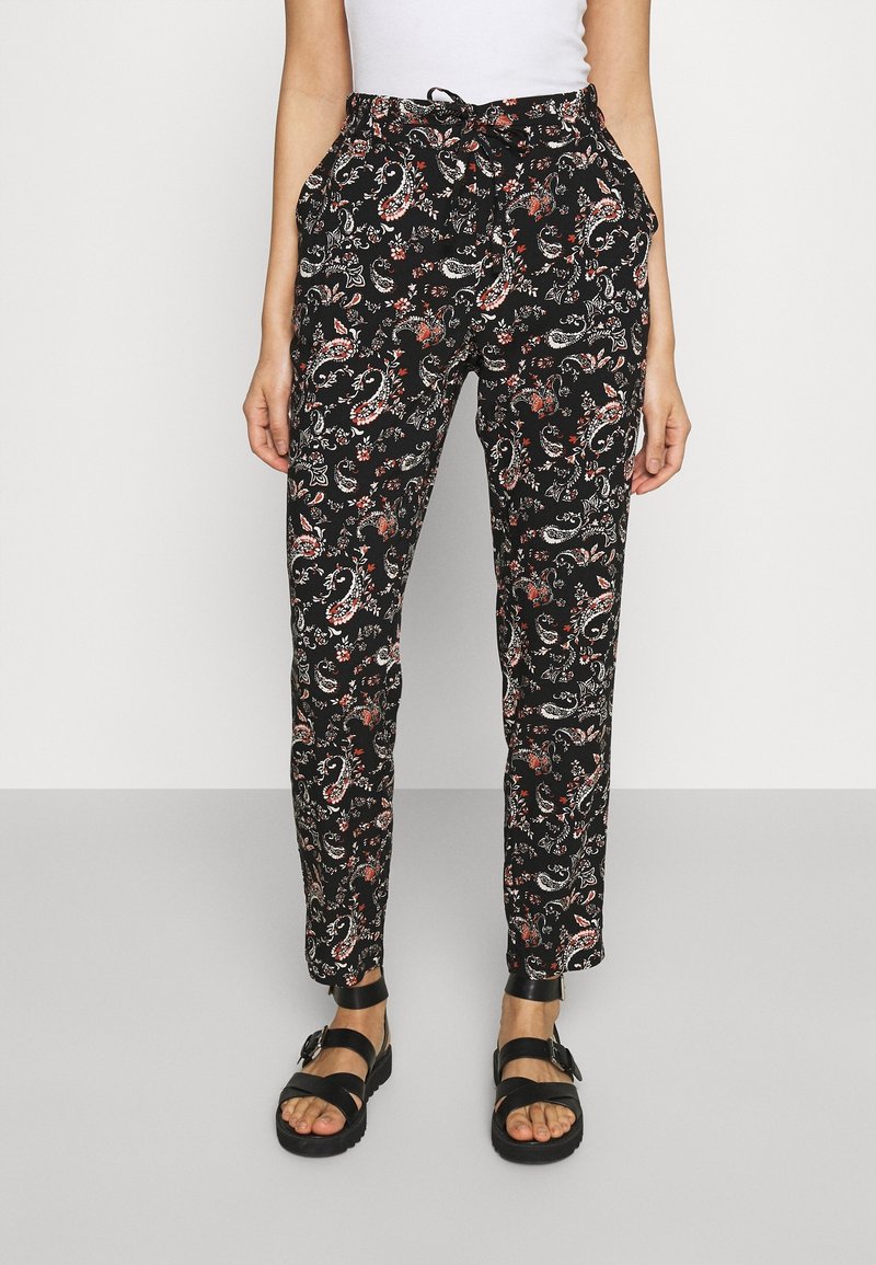 Black patterned trousers featuring a paisley design in red and white, with an elastic waistband and side pockets. Paired with black sandals.
