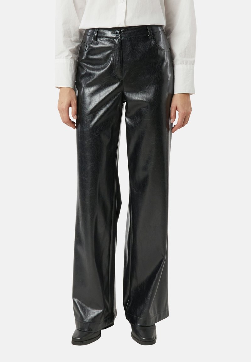 Czarne spodnie z szerokimi nogawkami wykonane ze sztucznej skóry o błyszczącym wykończeniu, z szlufkami, przednimi kieszeniami i wysokim stanem, w zestawieniu z czarnymi butami.